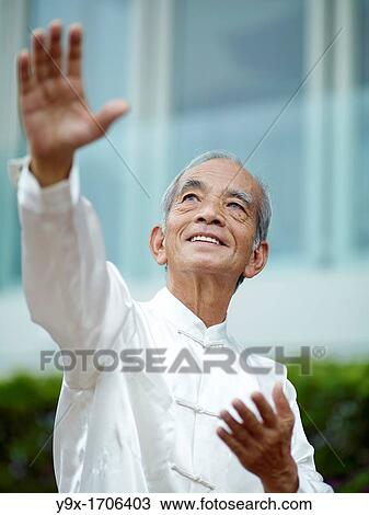 Stock Image - William Ng, a Tai Chi master practicing Tai Chi on the deck of The Peninsula Hotel, overlooking Hong Kong Victoria Harbour skyline. Fotosearch
