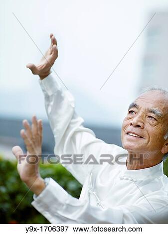 Stock Photo - William Ng, a Tai Chi master practicing Tai Chi on the deck of The Peninsula Hotel, overlooking Hong Kong Victoria Harbour skyline. Fotosearch