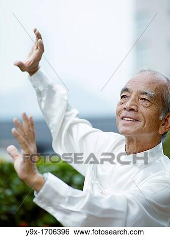 Stock Photograph - William Ng, a Tai Chi master practicing Tai Chi on the deck of The Peninsula Hotel, overlooking Hong Kong Victoria Harbour skyline. Fotosearch
