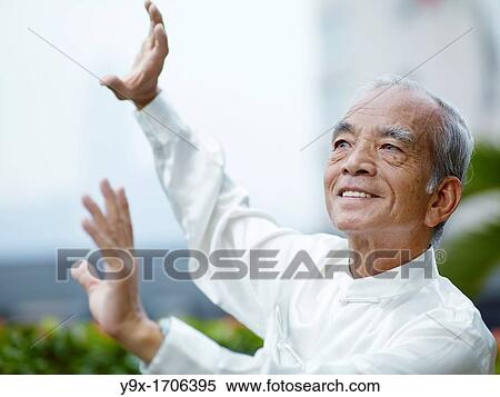 Stock Photography - William Ng, a Tai Chi master practicing Tai Chi on the deck of The Peninsula Hotel, overlooking Hong Kong Victoria Harbour skyline. Fotosearch