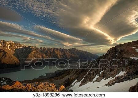 Stock Photograph - Wind clouds at dusk over Tasman Glacier Valley, from summit Mt Kinsey, Aoraki Mount Cook National Park, Canterbury New Zealand. Fotosearch