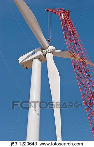 Stock Image - Wind turbine rotor moved into position by large crane during maintenance operation. Fotosearch