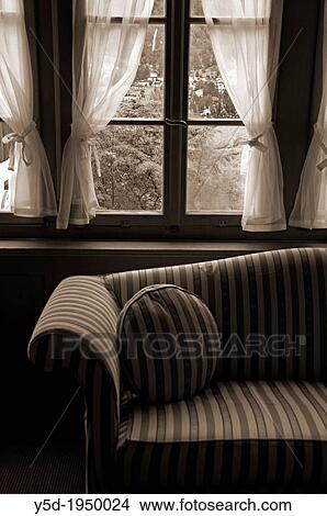 Picture - Windows with curtains next to couch, interior, symbol of privacy at home. Fotosearch