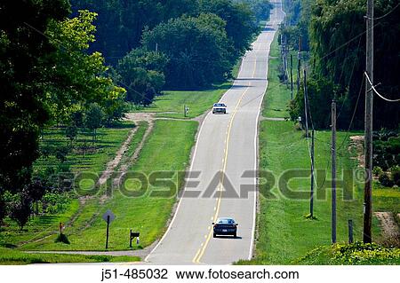 Stock Image - WISCONSIN. Kenosha County. Two land rural road through rolling hills, rural countryside in early fall, two vehicles on road. Fotosearch
