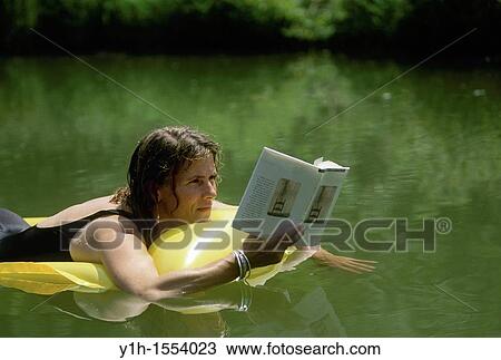 Woman, 30-40 years old, reading book while floating in water on an inflatable raft. Midwest, USA View Large Photo Image Stock Image - Woman, 30-40 years old, reading book while floating in water on an inflatable raft. Midwest, USA. Fotosearch