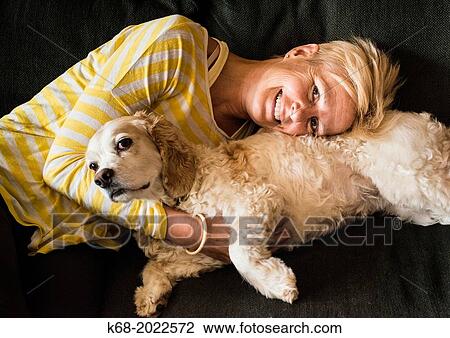 woman, 54, hugs a spaniel on a sofa View Large Photo Image Stock Image - woman, 54, hugs a spaniel on a sofa. Fotosearch