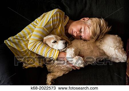 Stock Image - woman, 54, hugs a spaniel on a sofa. Fotosearch