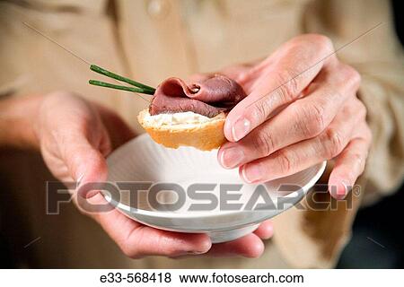 Stock Photo - Woman about to eat a beef tenderloin appetizer.. Fotosearch