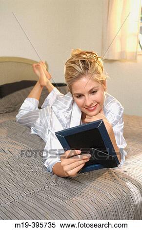 Stock Photography - woman admiring/looking at a photo. Fotosearch