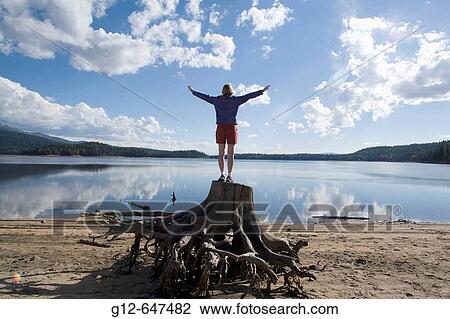 Woman, age 41, standing on tree stump raising her hands to a cloud filled sky. View Large Photo Image Stock Image - Woman, age 41, standing on tree stump raising her hands to a cloud filled sky.. Fotosearch