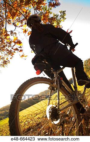 Stock Image - Woman alone outdoors on bicycle. Fotosearch