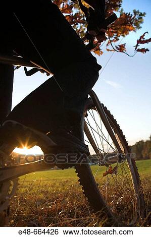 Stock Photograph - Woman alone outdoors on bicycle. Fotosearch