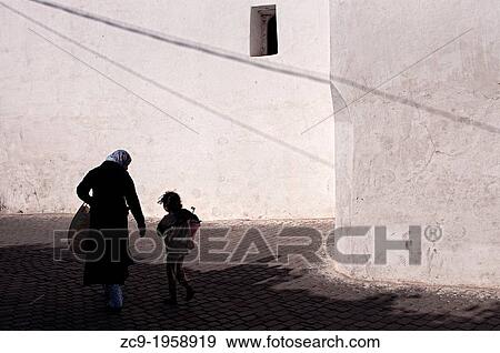 Woman and child walking by the streets of Azemmour medina, Morocco. View Large Photo Image Stock Photo - Woman and child walking by the streets of Azemmour medina, Morocco.. Fotosearch