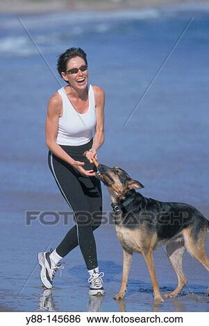 Stock Photograph - Woman and dog on the beach. Fotosearch
