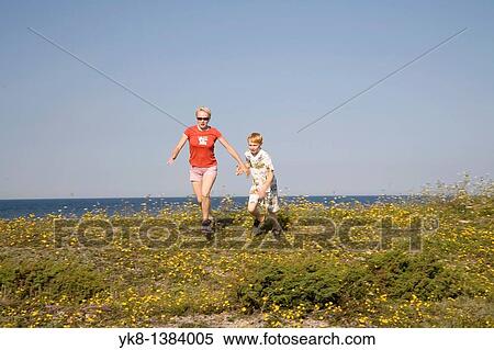 Stock Photography - Woman and Kid Running Hand in Hand on Saaremaa Coast, Saare County, Estonia. Fotosearch