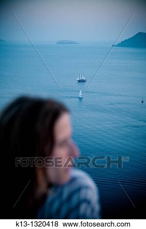 Stock Photo - Woman and sailboat in Oia Santorini Cyclades Islands Greece. Fotosearch