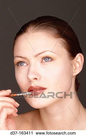 Stock Image - Woman applying lip-gloss. Fotosearch