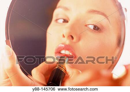 Stock Photograph - Woman applying lipstick. Fotosearch