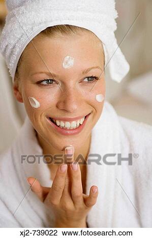 Stock Image - Woman applying moisturazing cream on her face. Fotosearch