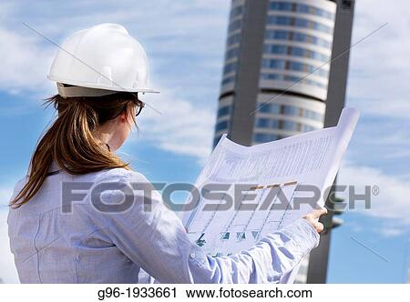 Stock Image - Woman architect with plans and helmet.. Fotosearch