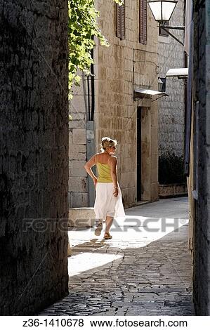 Stock Photo - Woman at narrow street in Trogir, Croatia. Fotosearch
