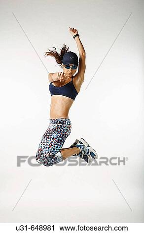 Stock Image - Woman athlete jumps in studio. Fotosearch