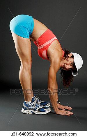 Stock Image - Woman athlete stretches in studio. Fotosearch