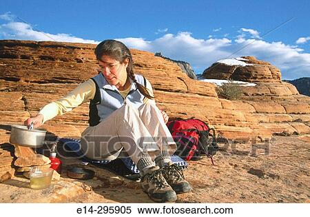 Stock Photography - Woman boiling water with a backpack stove. Zion National Park. Utah, USA. Fotosearch