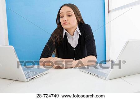 Woman bored in front of two laptops View Large Photo Image Stock Photo - Woman bored in front of two laptops. Fotosearch