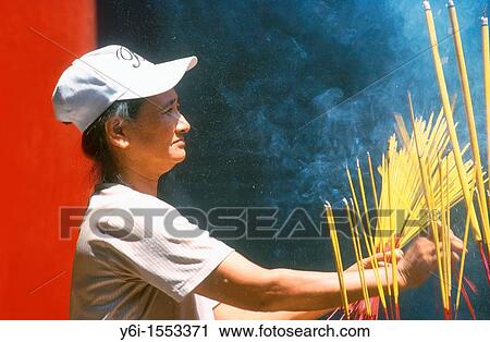 Woman burns incense sticks at temple in Ho Chi Minh City Vietnam View Large Photo Image Stock Image - Woman burns incense sticks at temple in Ho Chi Minh City Vietnam. Fotosearch