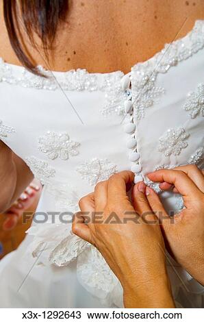 Woman buttoning up the bride's wedding dress View Large Photo Image Stock Image - Woman buttoning up the bride's wedding dress. Fotosearch