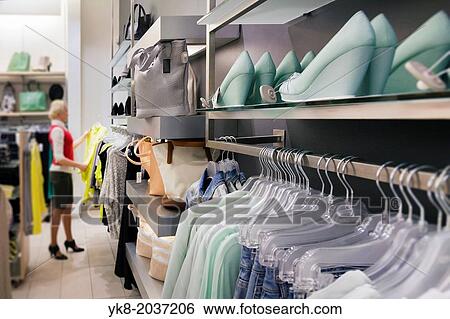 Woman, buyer in fashion shop aisle. Retail outlet with row of hangers, clothes. Fashion store interior. View Large Photo Image Stock Photograph - Woman, buyer in fashion shop aisle. Retail outlet with row of hangers, clothes. Fashion store interior.. Fotosearch