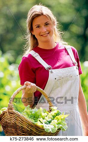 Stock Photograph - Woman carrying basket of lettuce. Fotosearch