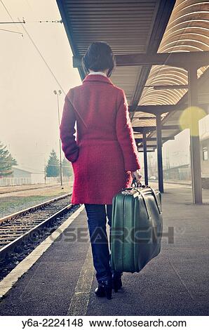Woman carrying suitcase standing on railroad station platform, rear view View Large Photo Image Stock Photo - Woman carrying suitcase standing on railroad station platform, rear view. Fotosearch