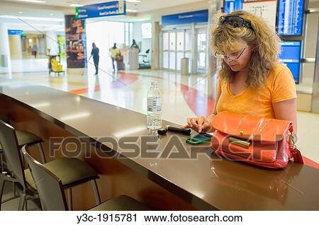 Woman checking her smartphone at airport, San Antonio, Texas, USA, Female 45 Caucasian View Large Photo Image Stock Image - Woman checking her smartphone at airport, San Antonio, Texas, USA, Female 45 Caucasian. Fotosearch