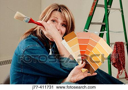 Stock Image - Woman choosing a colour for painting walls. Fotosearch