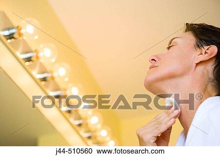 Stock Image - Woman cleaning face with cotton pad in the bathroom. Fotosearch