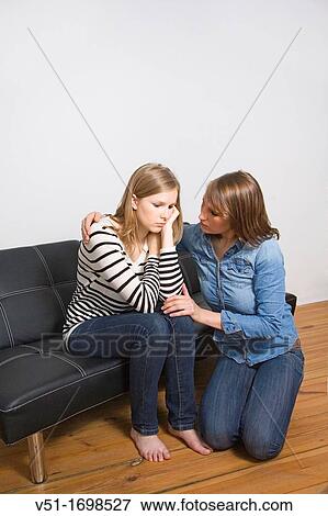 Stock Photo - Woman consolating her friend at home. Fotosearch