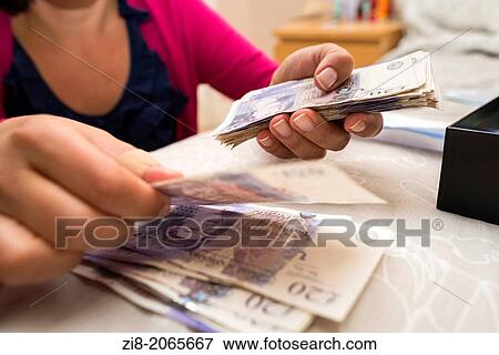Stock Photo - Woman counting money, UK pound sterling-close-up. Fotosearch