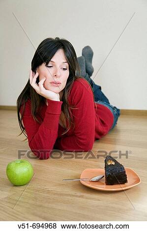 Stock Photo - Woman deciding about what to eat, healthy or not. Fotosearch