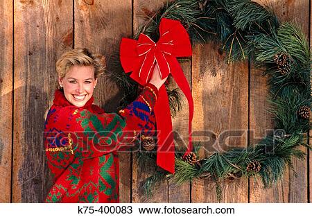 Stock Image - Woman decorating Christmas wreath. Fotosearch