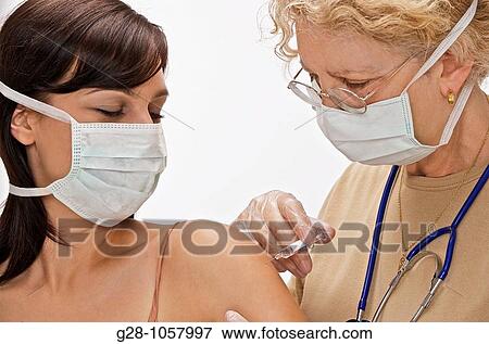 woman doctor giving an injection to a woman patient, both are wearing masks View Large Photo Image Stock Photo - woman doctor giving an injection to a woman patient, both are wearing masks. Fotosearch