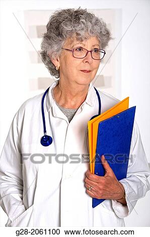 Woman doctor, in a white overall, senior woman with grey hair, red glasses and stethoscope around her neck, holding medical files in her hand, in hospital or clinic View Large Photo Image Stock Image - Woman doctor, in a white overall, senior woman with grey hair, red glasses and stethoscope around her neck, holding medical files in her hand, in hospital or clinic. Fotosearch