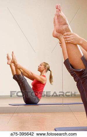 Stock Image - woman doing the open leg rocker, a pilates exercise. Fotosearch