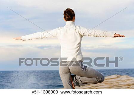 Stock Image - Woman doing yoga by the sea in Ibiza. Fotosearch