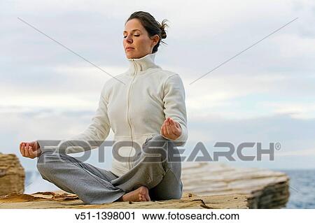 Stock Image - Woman doing yoga by the sea in Ibiza. Fotosearch