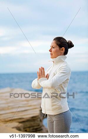 Stock Photo - Woman doing yoga by the sea in Ibiza. Fotosearch