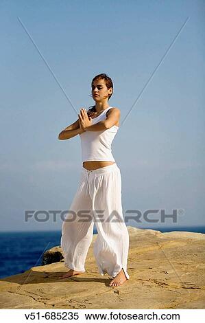 Stock Photography - Woman doing yoga by the sea. Fotosearch