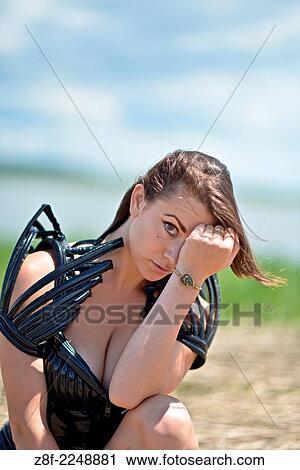 Stock Image - Woman dressed up with a futuristic space look costume holding a rusty trident, creating a modern interpretation of Salacia, Neptune's queen, an ocean Roman deity.. Fotosearch