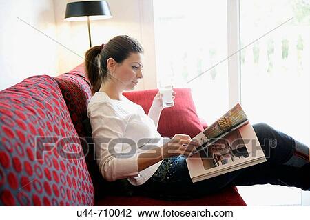 Woman drinking a milk glass reading a book relaxed on the sofa View Large Photo Image Stock Image - Woman drinking a milk glass reading a book relaxed on the sofa. Fotosearch